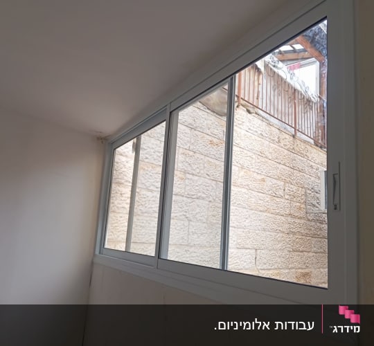 חלון אלומיניום עם מסגרת לבנה וקיר אבן בחוץ